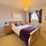Cosy bedroom with purple accents and wooden furniture.