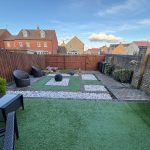 Modern garden with artificial grass and patio area.