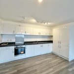 Modern kitchen with white cabinets and wood floor.