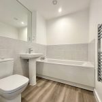 Modern white bathroom with tub, sink, and toilet.