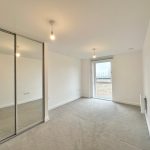 Unfurnished room with large mirrored wardrobe and windows.