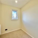 Small empty room with beige walls and window