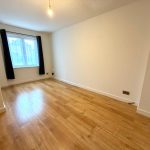 Empty room with wood flooring and window.