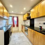 Modern kitchen with wooden cabinets, appliances, and red curtains.