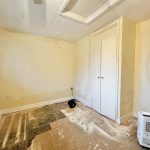 Empty room with peeling paint and unfinished floor.