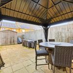 Patio with gazebo, table, chairs, and shed.
