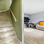 Staircase and living room with wooden flooring.