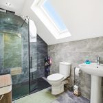 Modern grey-tiled bathroom with shower and skylight.