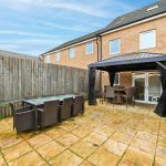 Modern patio with furniture and gazebo in backyard.