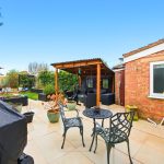 Outdoor patio with pergola, chairs, and garden view.