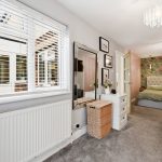Cosy bedroom with floral wallpaper and chandelier lighting.
