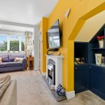 Cosy living room with yellow feature wall and fireplace.
