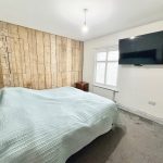 Bedroom with wooden feature wall and large TV