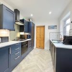 Modern kitchen with navy cabinets and wood floors.
