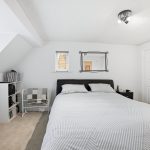 Modern bedroom with bed, shelves, and mirror.