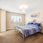 Modern bedroom with double bed and window view.