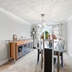 Modern dining room with glass table and cabinet.