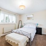 Bright bedroom with double bed and mirrored wardrobe.