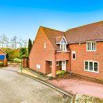 Red brick house with driveway and blue garage doors