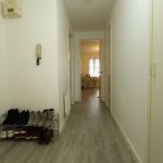 Hallway with shoe rack and view into room.