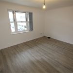 Bright empty room with wooden flooring.