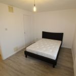 Minimalistic bedroom with bed and wooden floor.