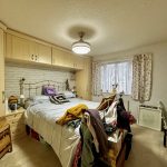 Cosy bedroom with cluttered bed and wooden wardrobes.