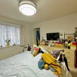 Cluttered bedroom with unmade bed and messy dresser.