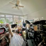 Cluttered conservatory with drum set and storage items.