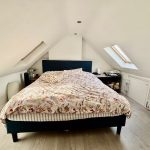 Cosy attic bedroom with large bed and skylights.