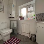 Modern bathroom with boiler, window, and striped rug.